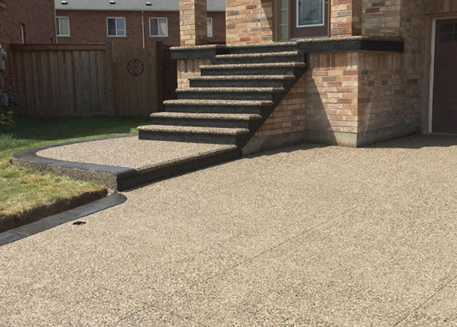 Exposed aggregate driveway and staircase with dark stamped concrete edging