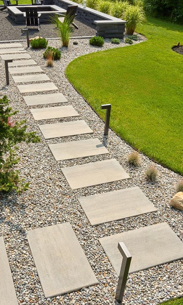 Poured concrete slab walkway set in river rock beside a manicured lawn
