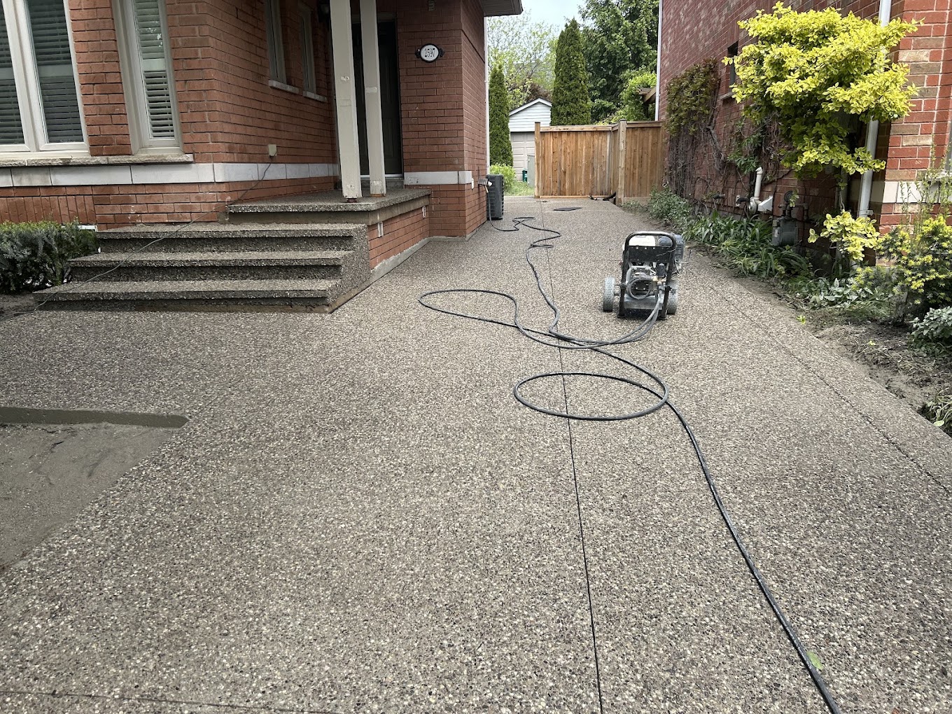 Wide exposed aggregate side driveway running between two brick homes