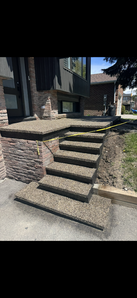 Exposed aggregate front porch and steps with dark stamped nosing over a stone wall